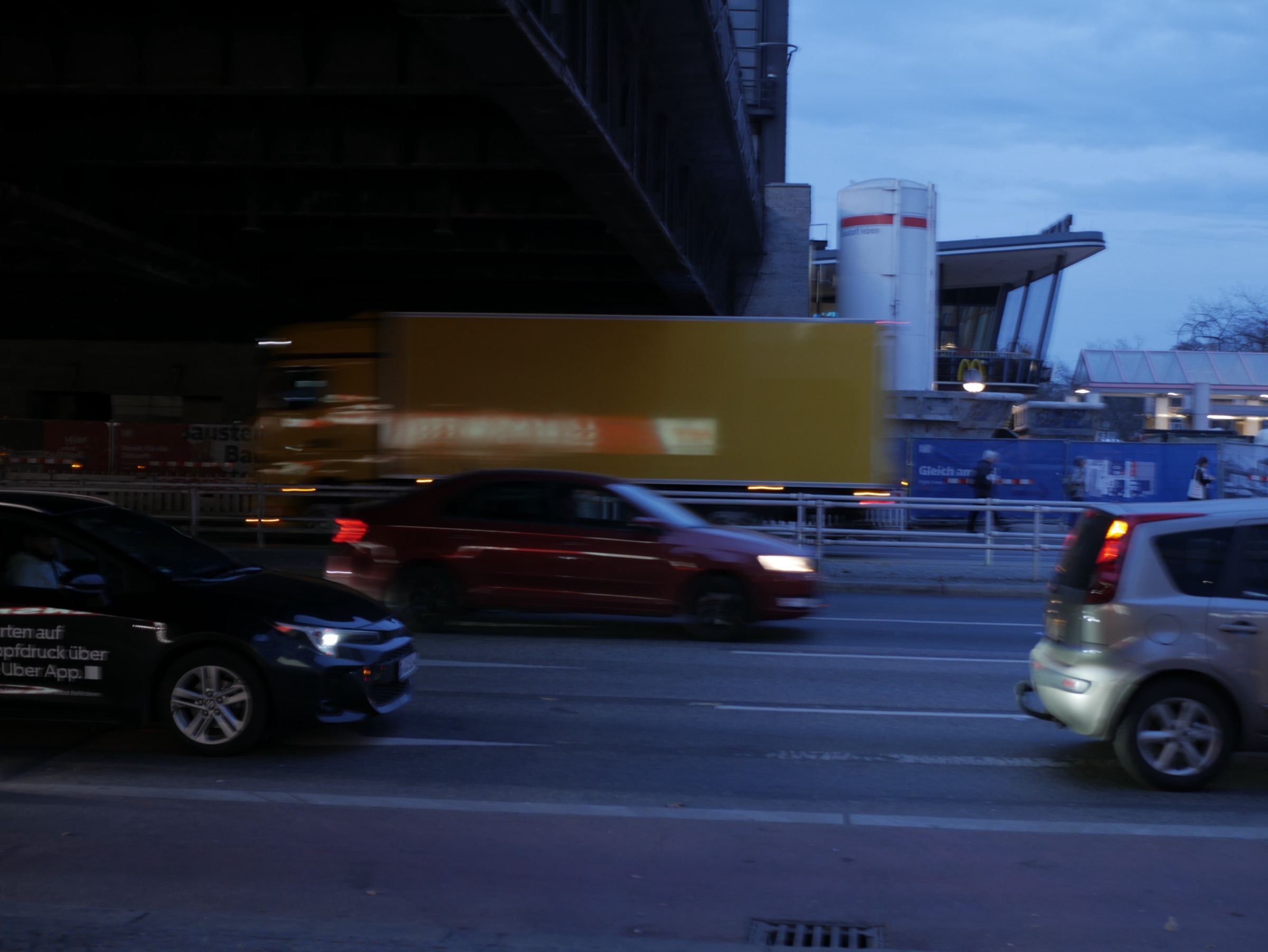 Autos en movimiento bajo un puente al atardecer
